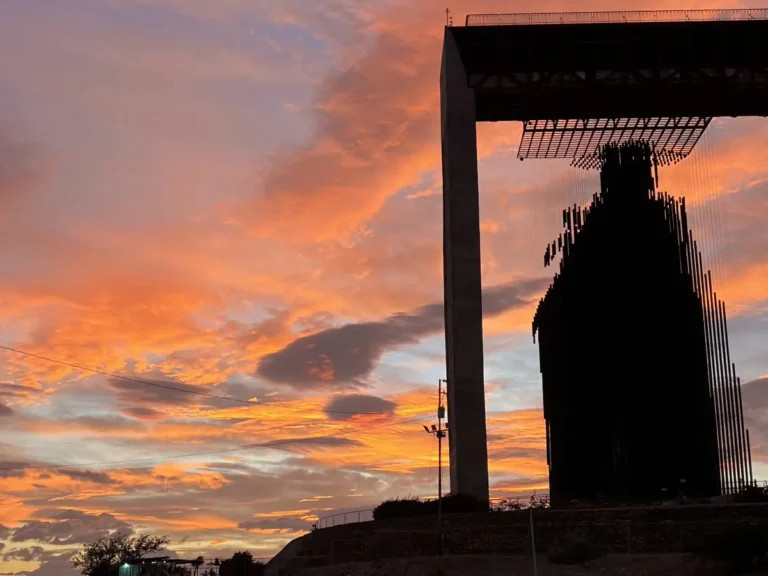 Silueta del monumento Manto de María en Barquisimeto al atardecer, con el cielo naranja y nubes