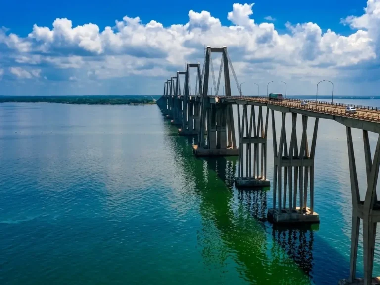 Puente sobre el Lago de Maracaibo con pilares en forma de V reflejados en el agua bajo un cielo con nubes