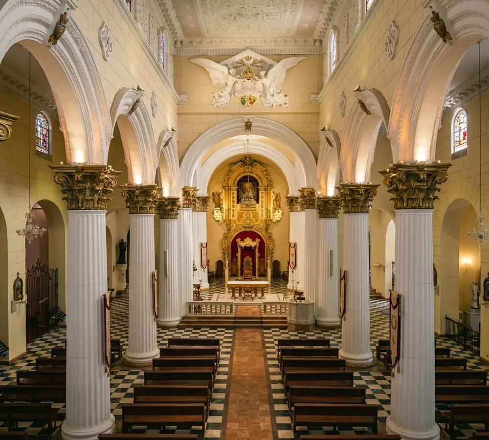 Interior de la Catedral de Valencia, Venezuela, con columnas blancas, arcos y el altar dorado al fondo